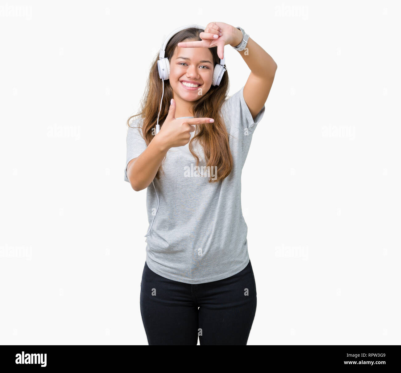 Young beautiful woman wearing headphones listening to music over isolated background smiling making frame with hands and fingers with happy face. Crea Stock Photo