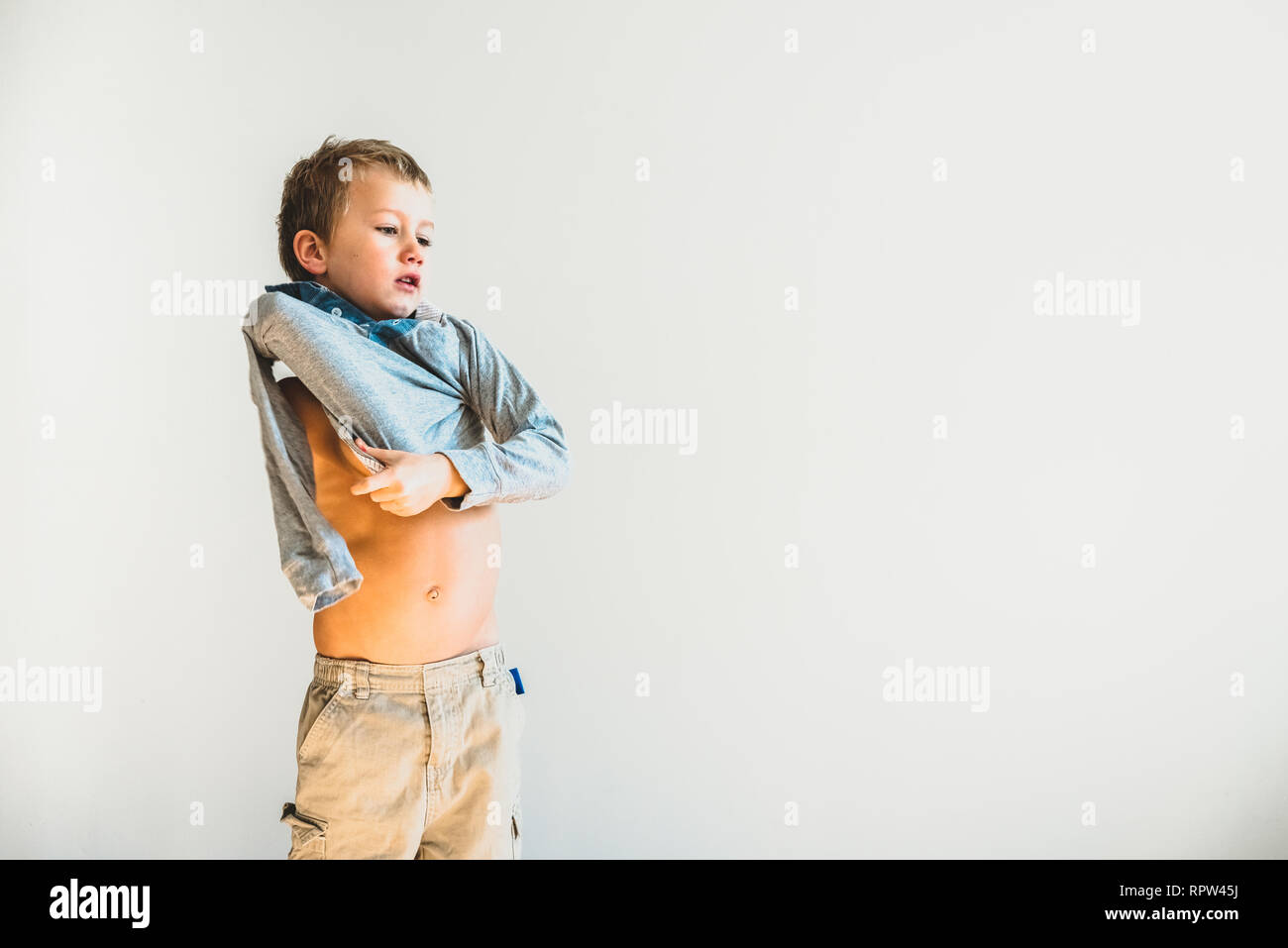 Child trying to take off his shirt and undress on his own Stock Photo