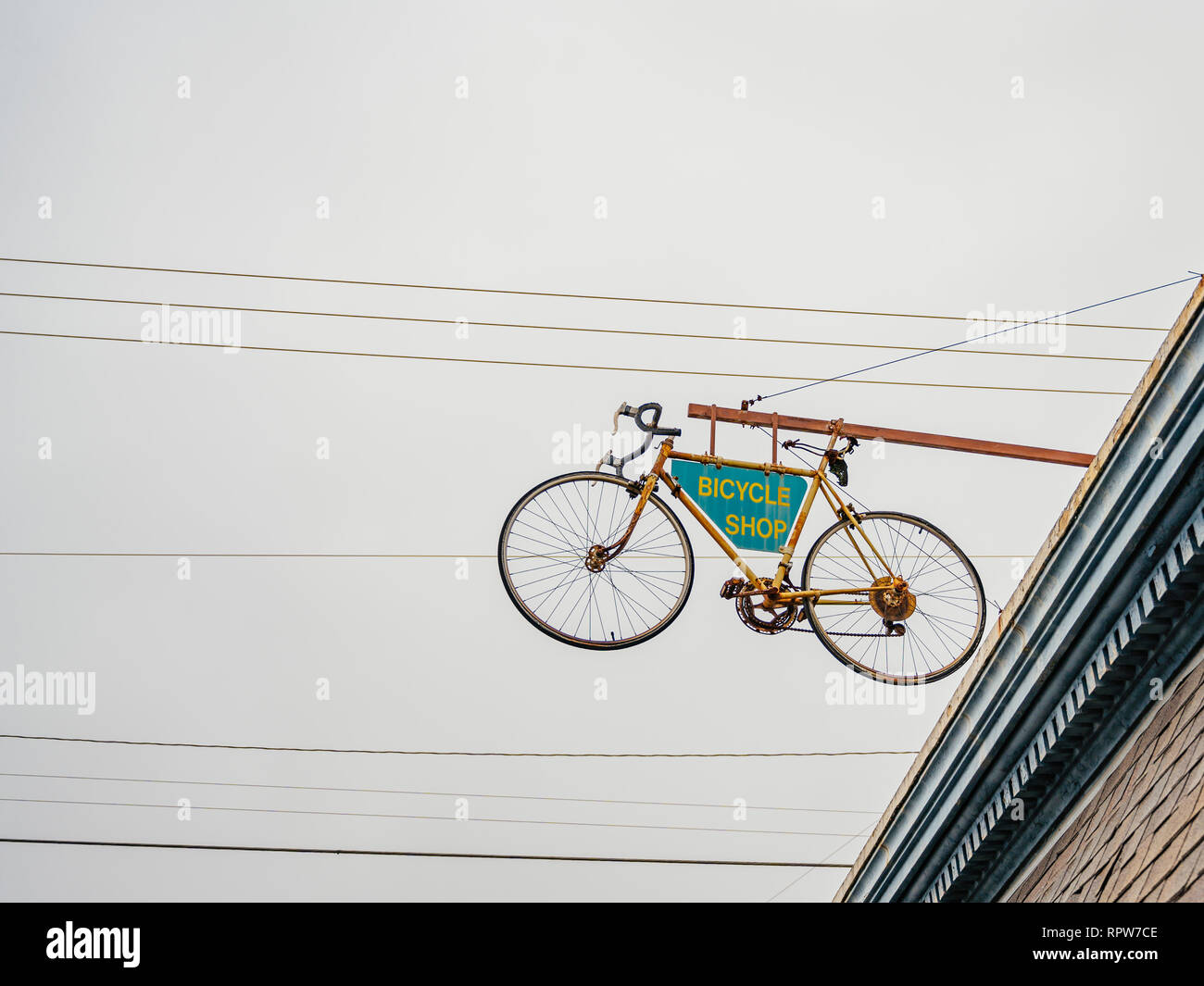 Bicycle shop sign attached to a suspended bicycle over the exterior front entrance to the business, a unique advertising idea, in Montgomery Alabama. Stock Photo