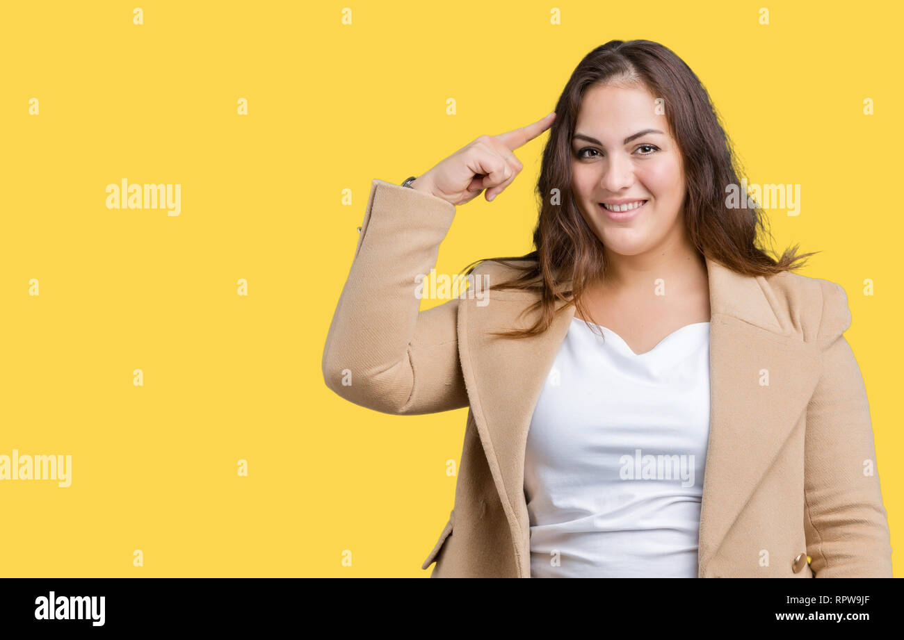 Beautiful plus size young woman wearing winter coat over isolated background Smiling pointing to head with one finger, great idea or thought, good mem Stock Photo