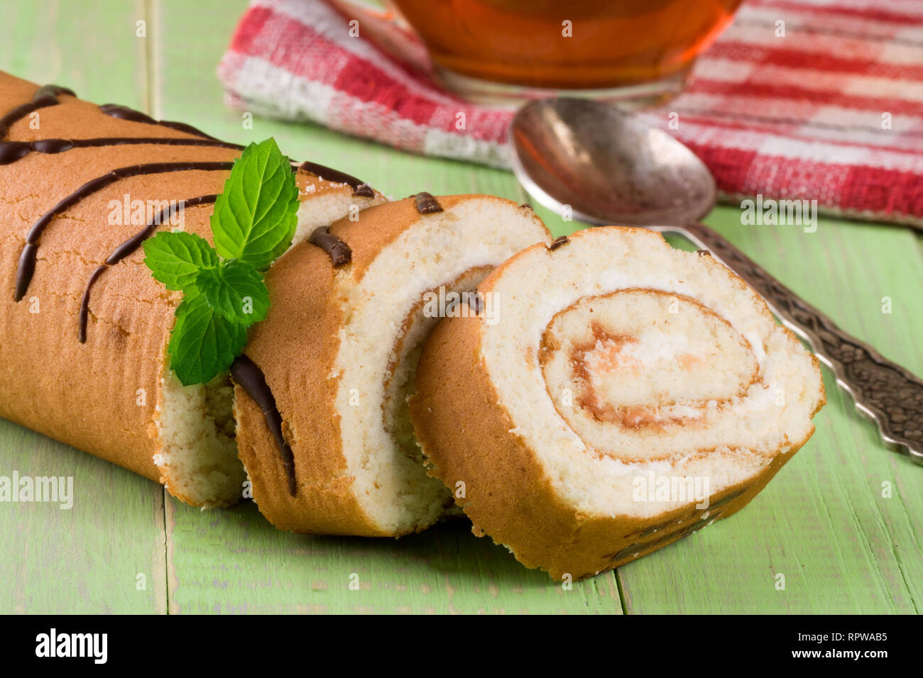 Biscuit swiss roll on green wooden background Stock Photo