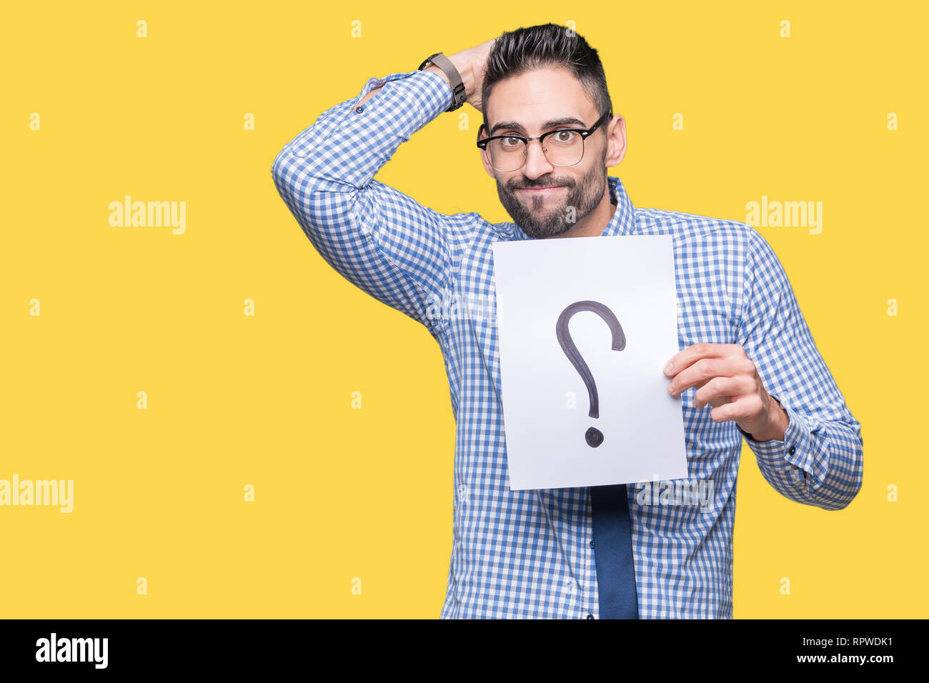 Handsome young business man holding paper with question mark over isolated background stressed with hand on head, shocked with shame and surprise face Stock Photo