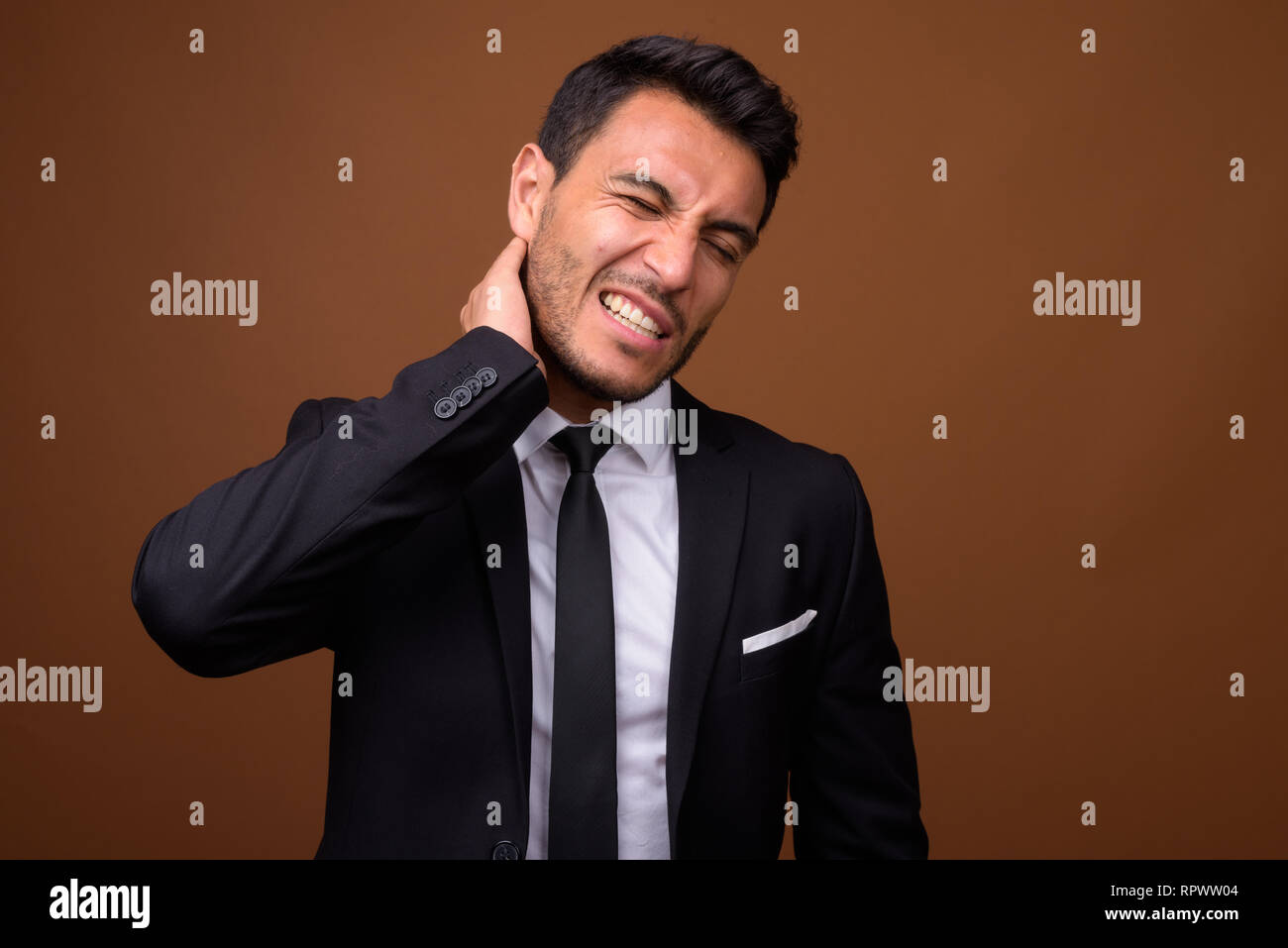 Young handsome Hispanic businessman against brown background Stock Photo