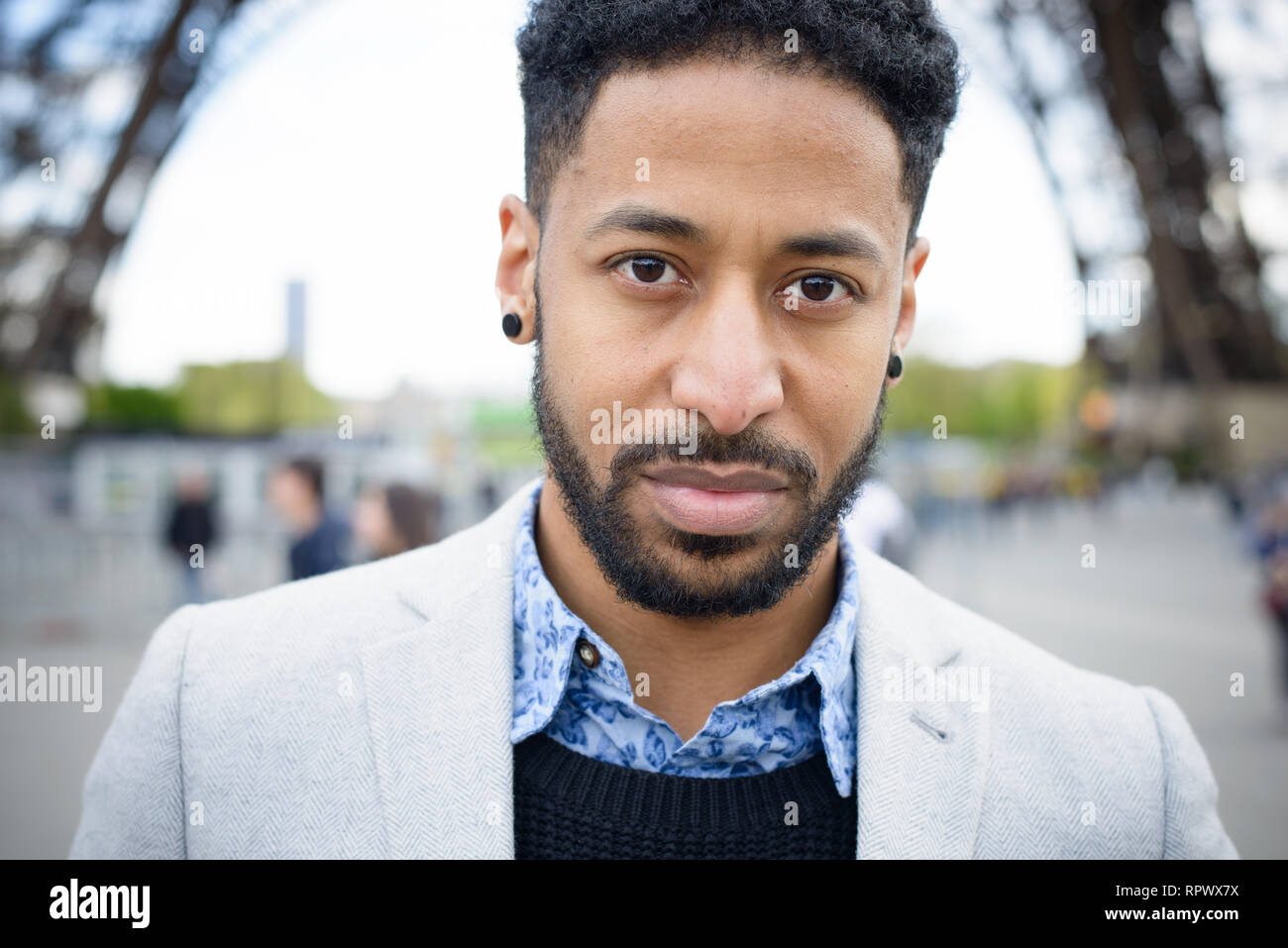 Portrait of serious, fashionable young man of African descent under the Eiffel tower in Paris, France. Stock Photo