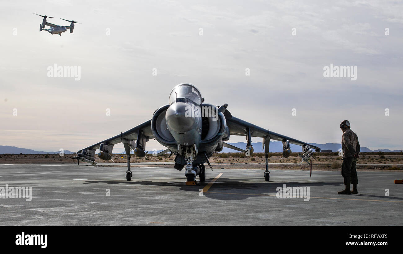 A maintainer with Marine Attack Squadron (VMA) 311, Marine Aircraft Group (MAG) 13, 3rd Marine Aircraft Wing (MAW), prepares to launch the first of 11 AV-8B Harriers while an MV-22B Osprey with MAG-39 flies overhead at Marine Corps Air Ground Combat Center Twentynine Palms, Calif., Feb. 15. Over the course of several hours, more than 100 aircraft from MAG-13 and MAG-39 took to the skies over Southern California, proving 3rd MAW's capability to "Fix, Fly, Fight" and, when needed, advance at a moment's notice. (U.S. Marine Corps photo by Sgt. David Bickel) Stock Photo