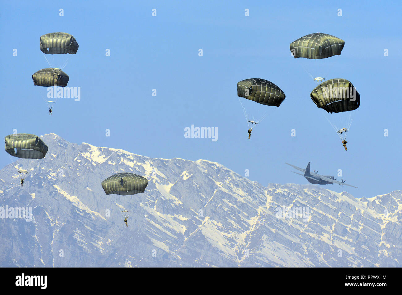 U.S. Army Paratroopers, assigned to the 173rd Brigade Support Battalion, 173rd Airborne Brigade, prepare to land after exiting U.S. Air Force C-130 Hercules aircraft from the 86th Air Wing during airborne operation at Juliet Drop Zone, Pordenone, Italy, Feb. 21, 2019. The 173rd Airborne Brigade is the U.S. Army Contingency Response Force in Europe, capable of projecting ready forces anywhere in the U.S. European, Africa or Central Commands' areas of responsibility. (U.S. Army Photo by Paolo Bovo) Stock Photo