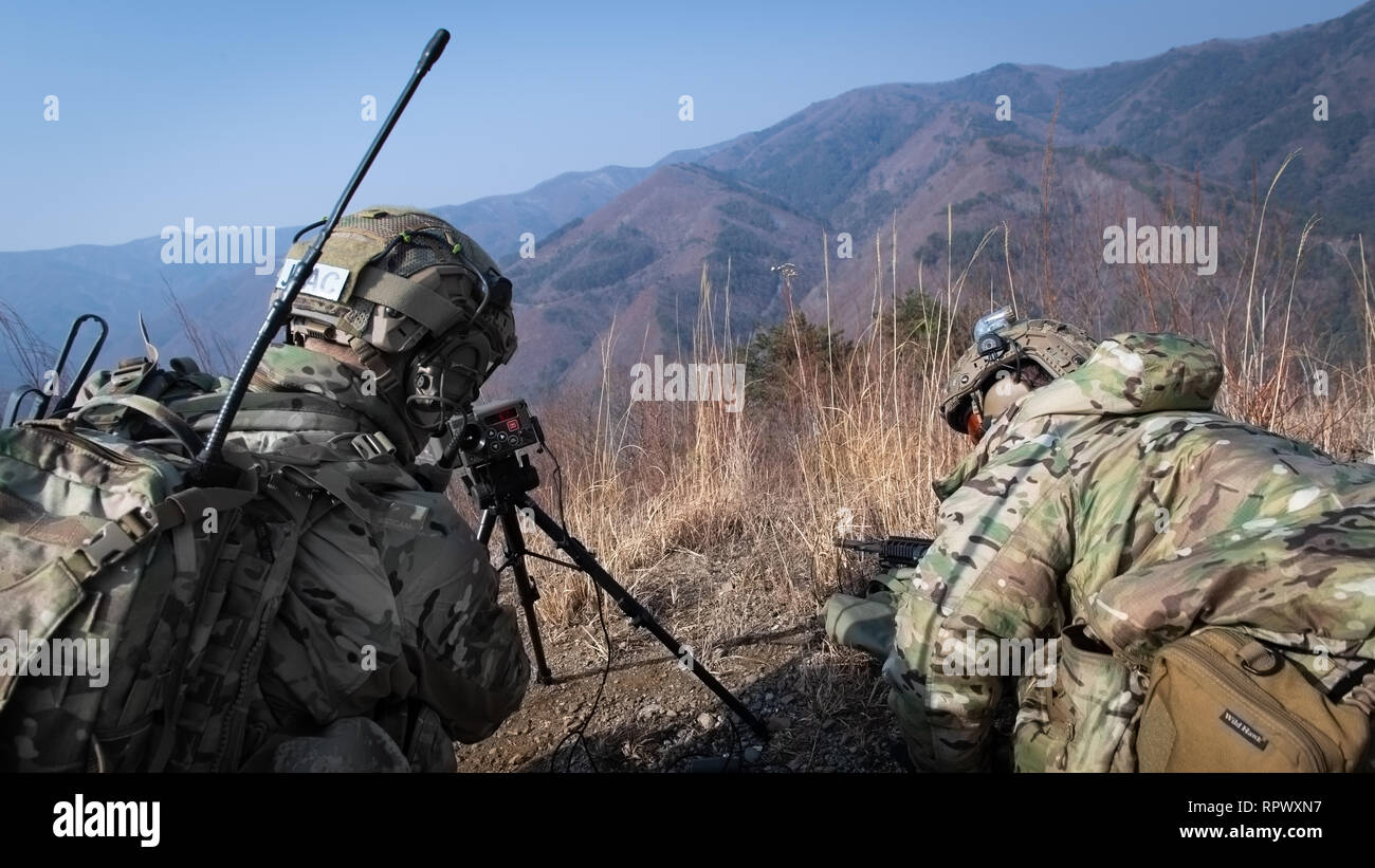 Two U.S. Air Force joint terminal attack controllers utilize a laser designator designed to designate a target during training at Pilsung Range in Gangwan Province, Republic of Korea, Feb. 14, 2019. Laser designators are used to provide targeting designator for laser-guided bombs, missiles or precision and artillery munitions and was used to improve the A-10 Thunderbolt II’s ability to accurately strike its target. (U.S. Air Force photo by Staff Sgt. Benjamin Raughton) Stock Photo