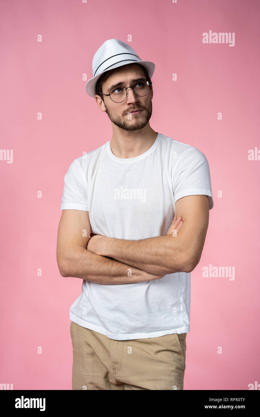 Portrait of the young thinking man looks up - isolated on pink Stock Photo