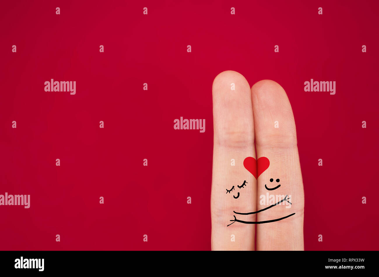 fingers coupled together with a painted heart, a cheerful smile, smileys, emojis, isolated on red background, the symbol of lbwi, relationships Stock Photo