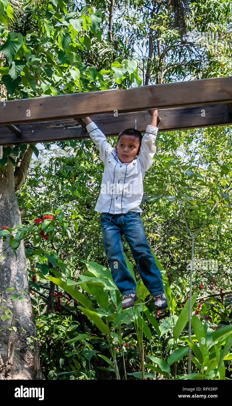 latin child playing on monkey bars in Guatemalan playground Stock Photo