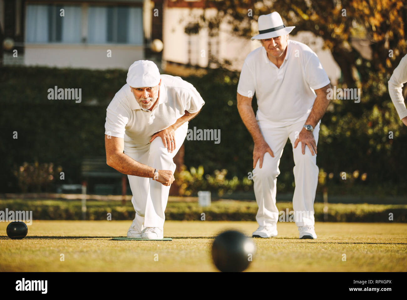 Two senior men playing boules in a park. Elderly men enjoying a game of boules in a lawn on a sunny day. Stock Photo