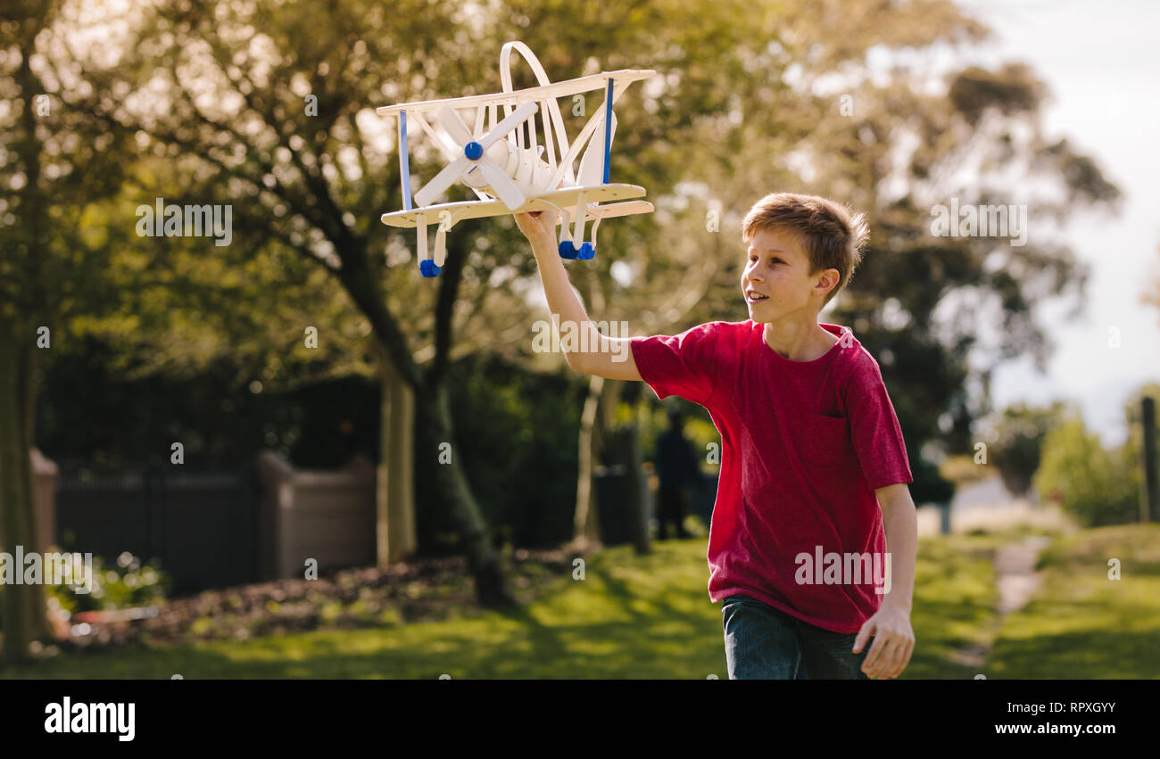Boy playing with a toy plane in the park on a summer day. Boy running ...