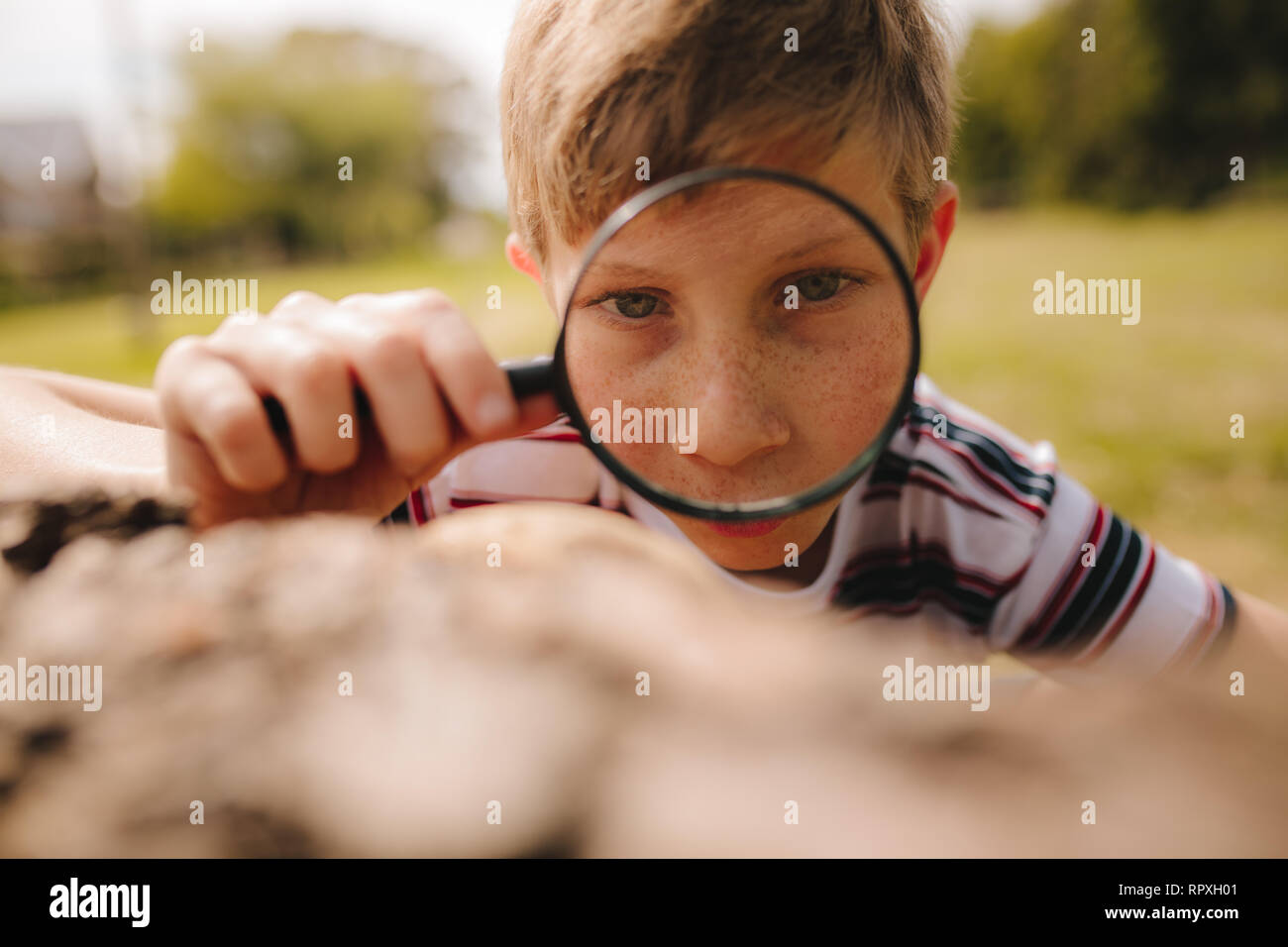 Closeup of cute kid with magnifying glass outdoors. Boy exploring with ...