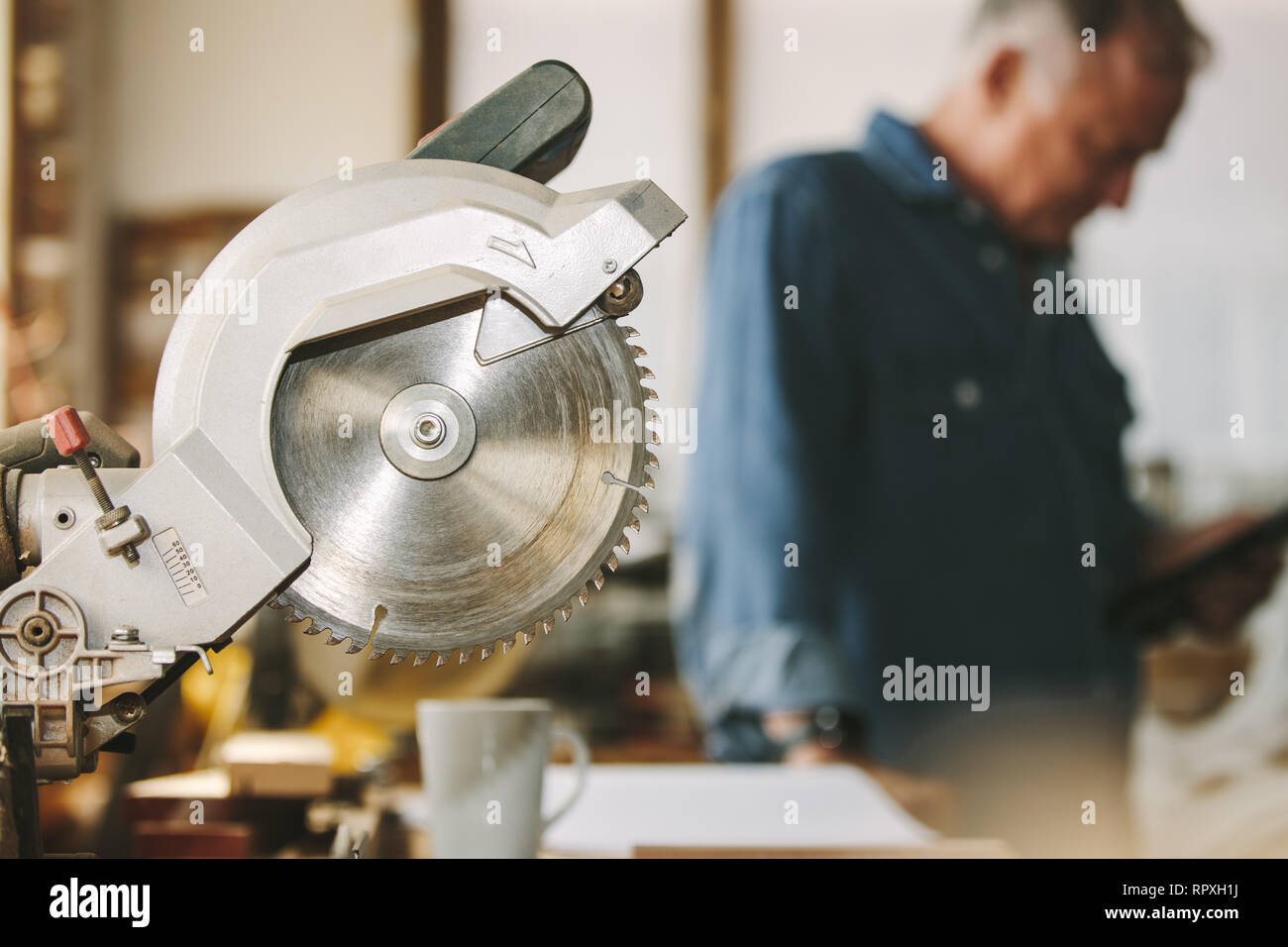 Circular wood saw in carpentry with carpenter in background