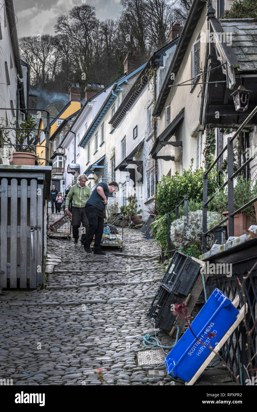 Two men deliver winter supplies by a traditional sledge to the residents in the High Street at Clovelly in North Devon. Set into a steep hillside, sle Stock Photo
