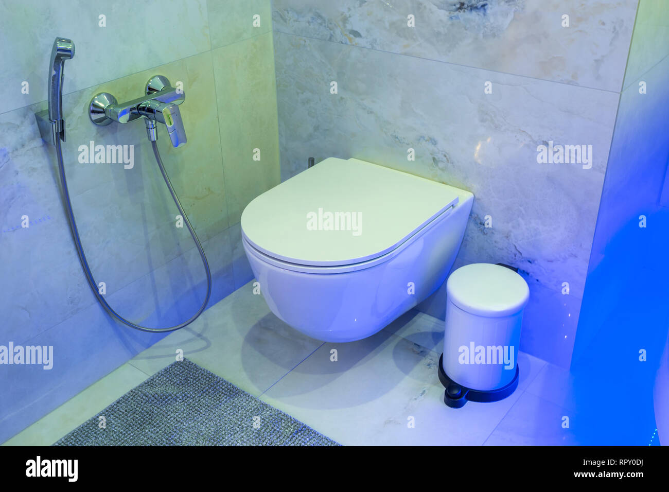toilet and detail of a corner shower bidet with soap and shampoo dispensers  on wall mount shower attachment in neon light Stock Photo - Alamy