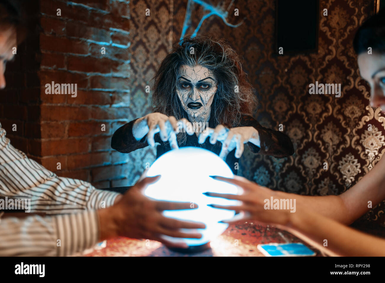 Female foreteller calls the spirits over a crystal ball, witchcraft. Scary  witch reads a magic spell, young people hands up on spiritual seance Stock  Photo - Alamy