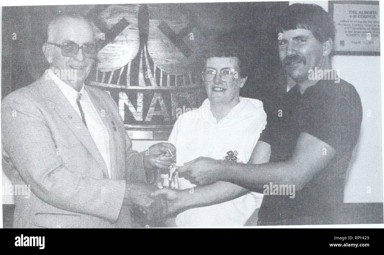 . Agri-news. Agriculture. Battle Lake Centre open to the public (cont'd). Herman Crosfield, left, president of the Alberta 4-H Foundation turns over the keys to the Battle Lake Centre to the new facility managers, Adele Reichert and John McKechnie. The centre is now open for bookings by groups and associations.. Please note that these images are extracted from scanned page images that may have been digitally enhanced for readability - coloration and appearance of these illustrations may not perfectly resemble the original work.. Alberta. Alberta Agriculture. Communications Branch; Alberta. Alb Stock Photo