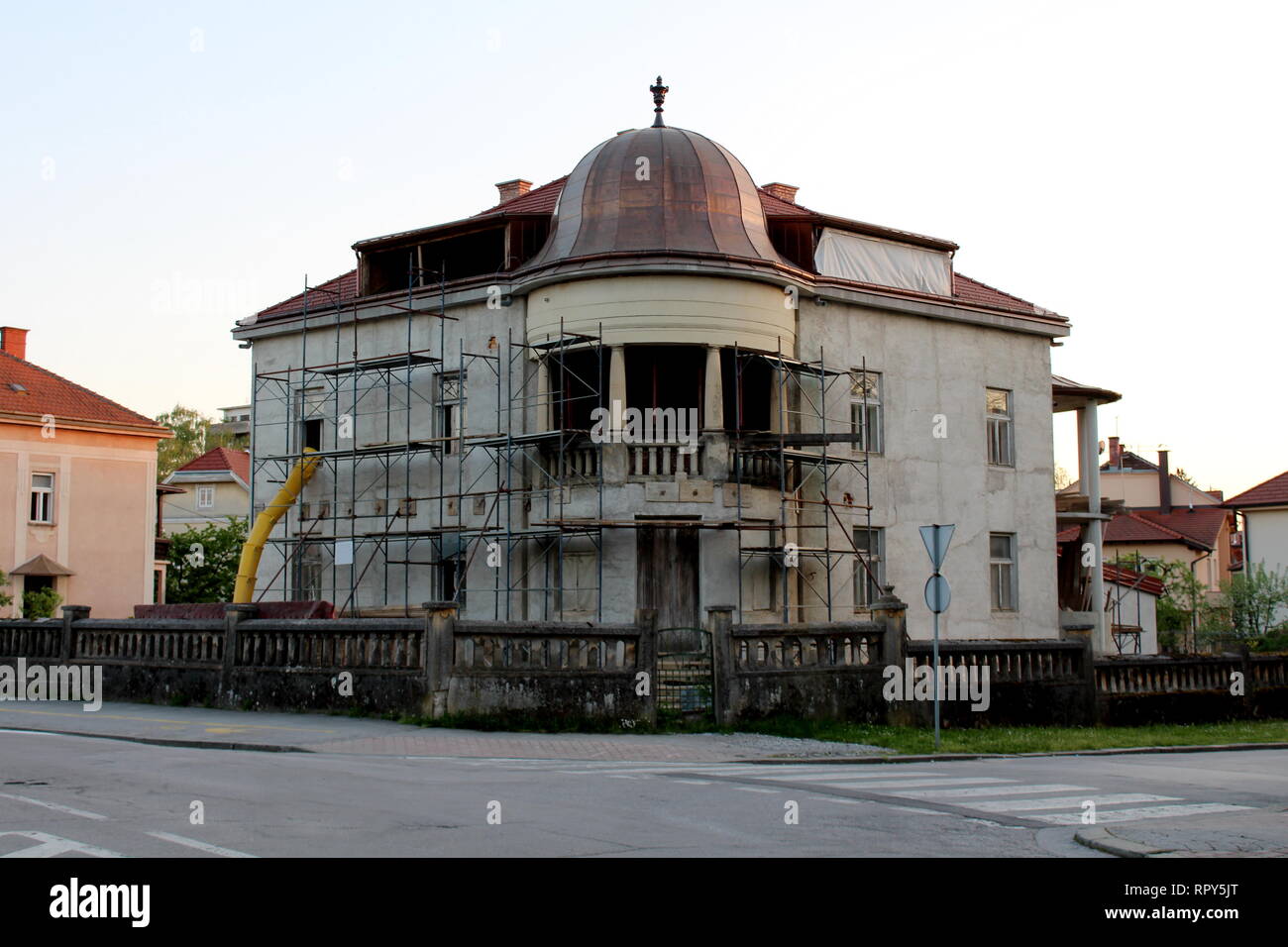 Old villa under complete reconstruction from outer facade to inner rooms with scaffolding and construction material located on crossroads Stock Photo
