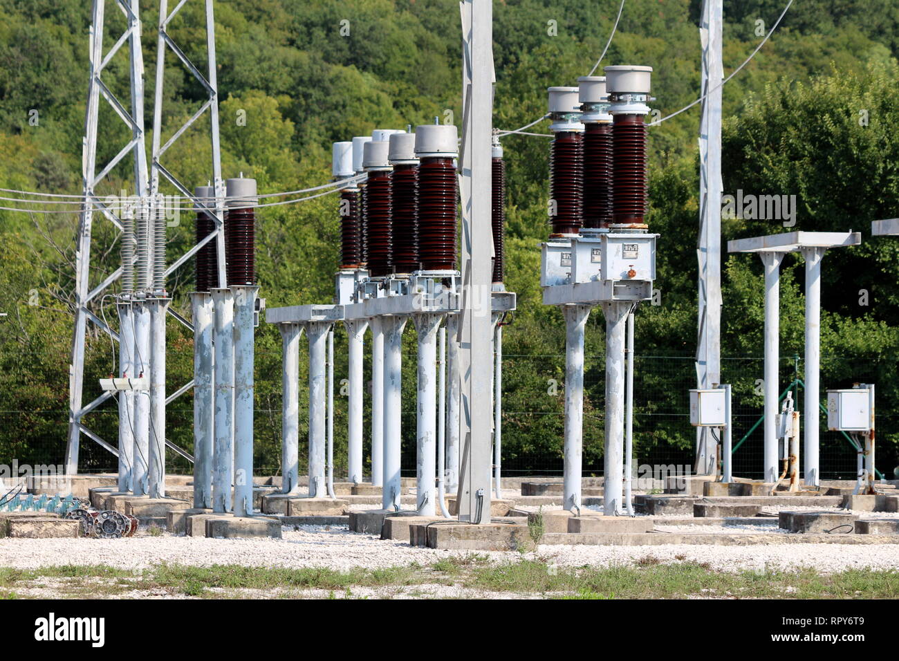 Tall dark brown ceramic insulators mounted on strong metal pipes and connected with electrical wires inside local power plant Stock Photo