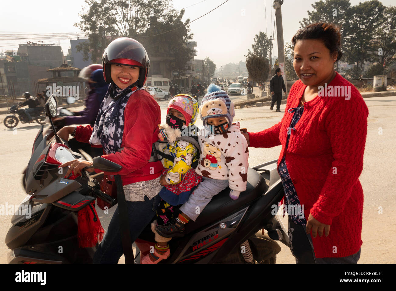 Nepal, Kathmandu, Thamel, Swayambhu Marg, woman carrying two young children on motorbike, outside Indrani and Mahadev temples Stock Photo