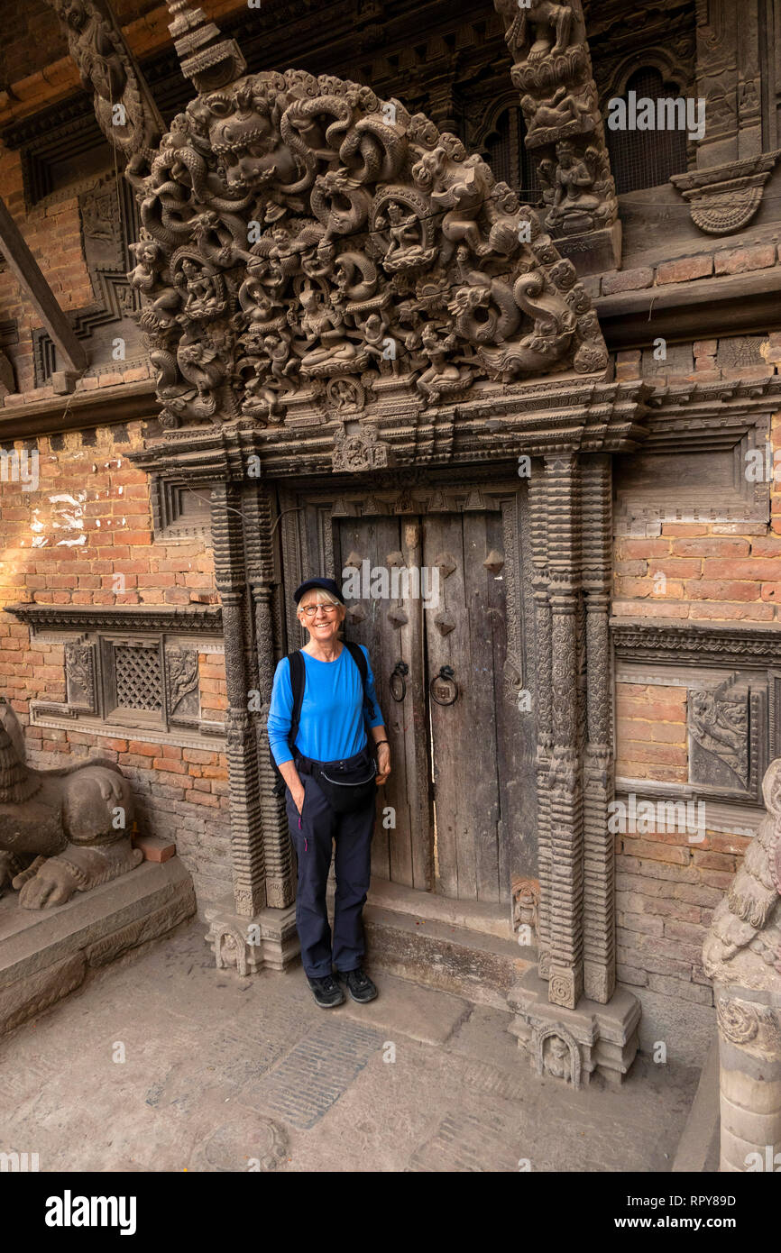 Nepal, Kathmandu, city centre,  Jyatha Marg, Chhusya Bahal, tourist standing below ancient carved torana above temple doorway Stock Photo