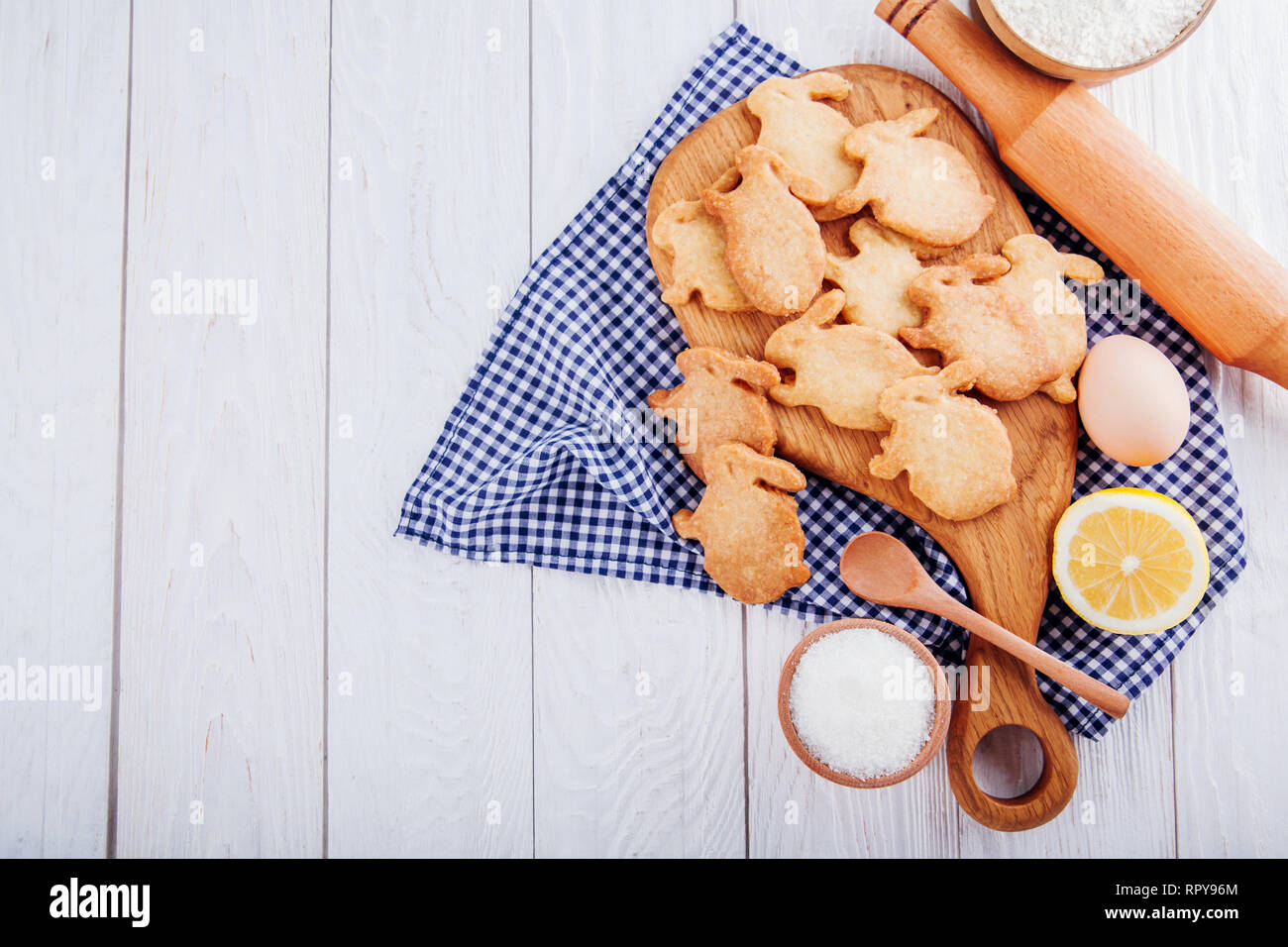 Bunny shaped cookies with ingredients on wooden background Recipe of