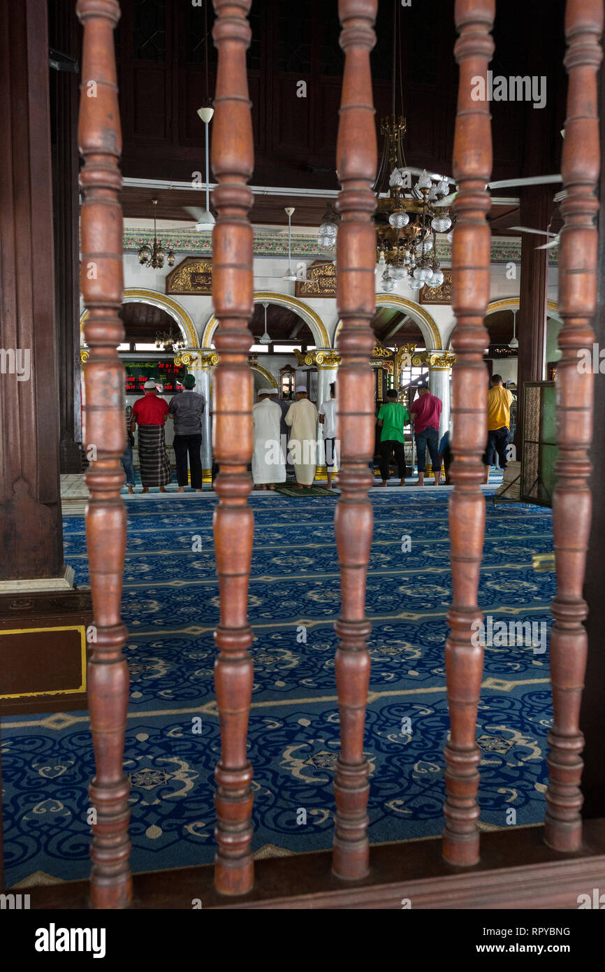 Malaysian-style Spindles in Window of Kampung Kling Mosque, Masjid Kampung Kling, Melaka, Malaysia.  Men at Prayer inside. Stock Photo