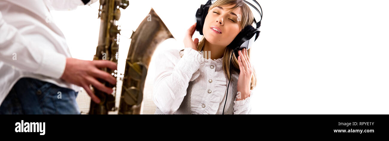 Lovely girl in headphones listening music enjoy sax tune man and woman studio shot over white panoramic background copyscape for your text Stock Photo