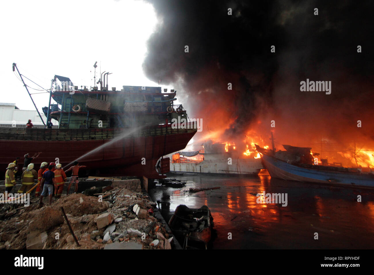 Jakarta, Indonesia. 23rd Feb, 2019. Firefighters try to extinguish the burning fishing boats at Muara Baru Port in Jakarta, Indonesia. Feb. 23, 2019. Credit: Krisnada/Xinhua/Alamy Live News Stock Photo