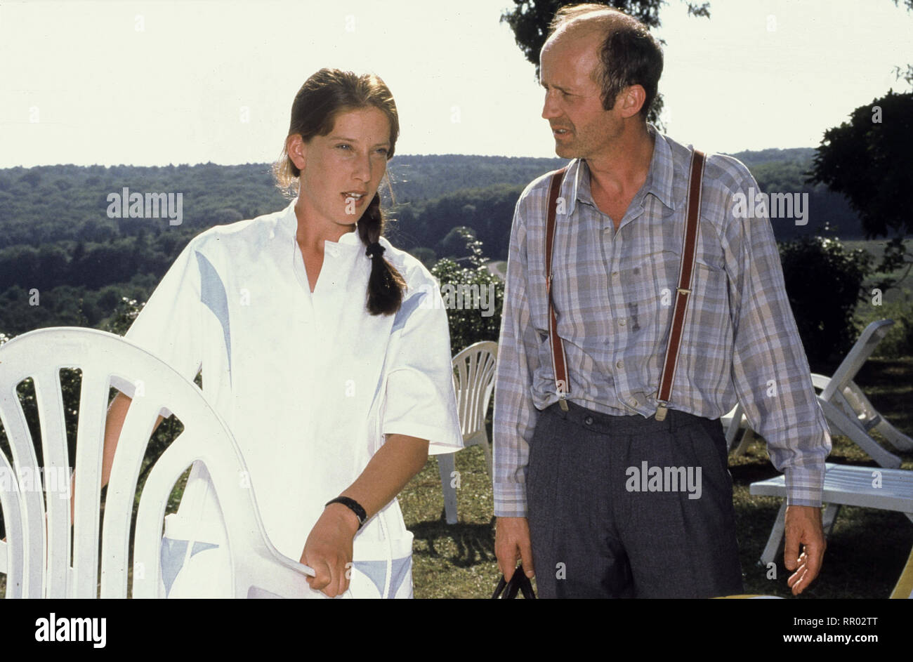 KURKLINIK ROSENAU / Die Rettung Deutschland 1996 / Herrmann Zschoche Mit einer Verletzung am Bein taucht der Landstreicher Heinz in 'Rosenau' auf. Dr. Tannert befürchtet eine Blutvergiftung und behält ihn deshalb noch für einige Tage in der Klinik, was den anderen Kurgästen gar nicht passt. Szene mit SABINE WOLF (Schwester Chris) und CHRISTOF WACKERNAGEL (Heinz) EM / Überschrift: KURKLINIK ROSENAU / Deutschland 1996 Stock Photo