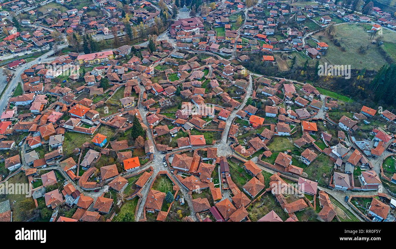 Panoramic drone view of small village in the mountains with old typical traditional houses against green hills and dynamic blue sky with contrast Stock Photo