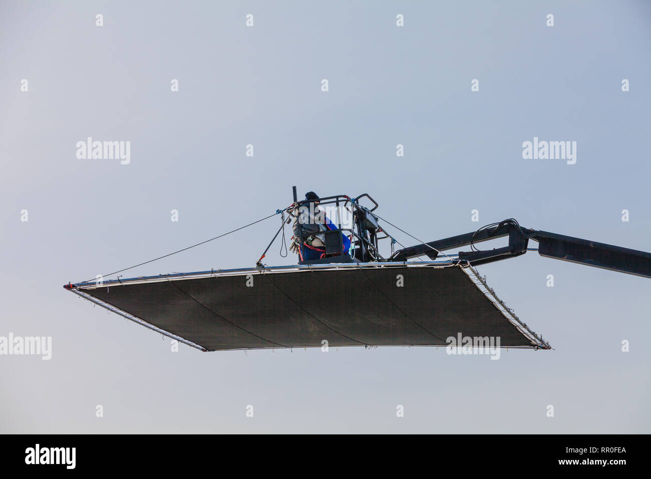 Film crew operator controlling the position and angle of a shade screen ...