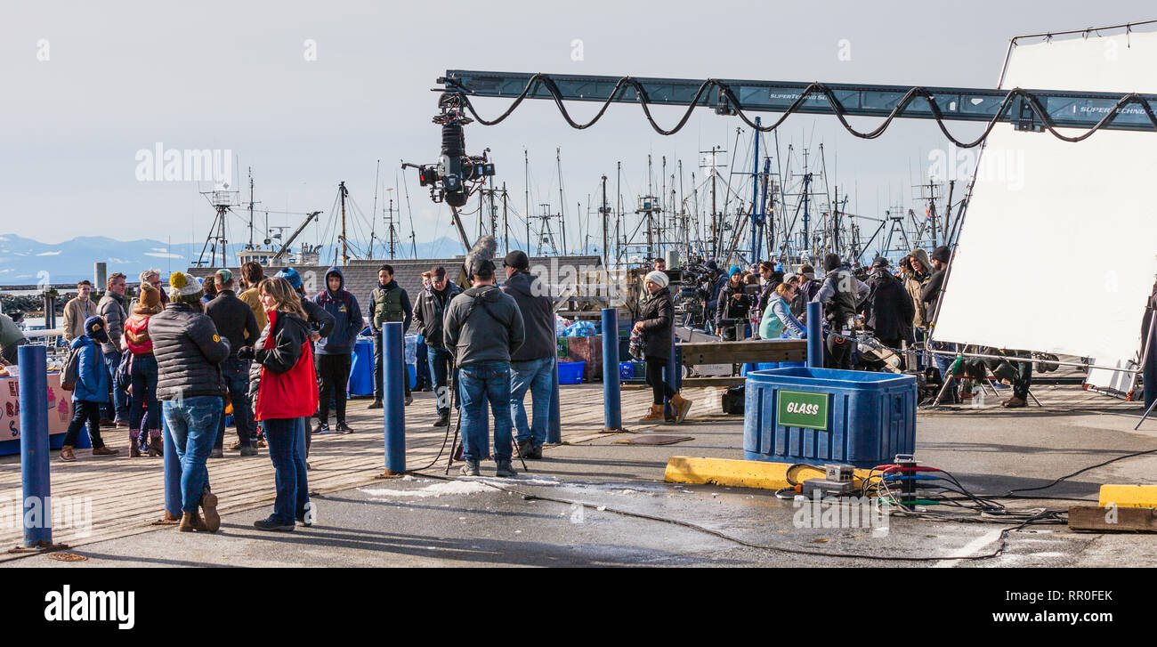 Film crew and actors between takes at a waterfront location Stock Photo