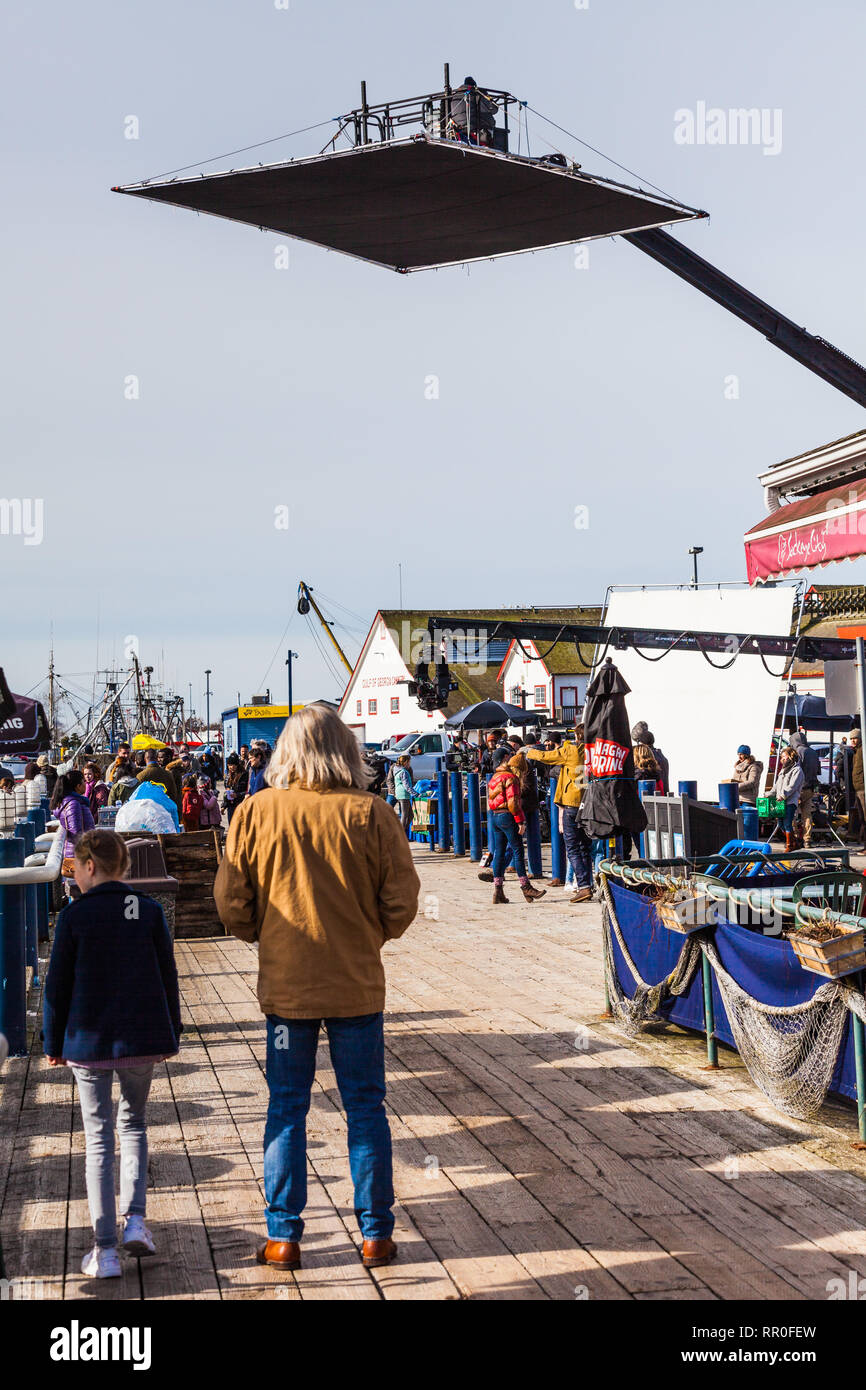 Film crew and actors between takes at a waterfront location Stock Photo