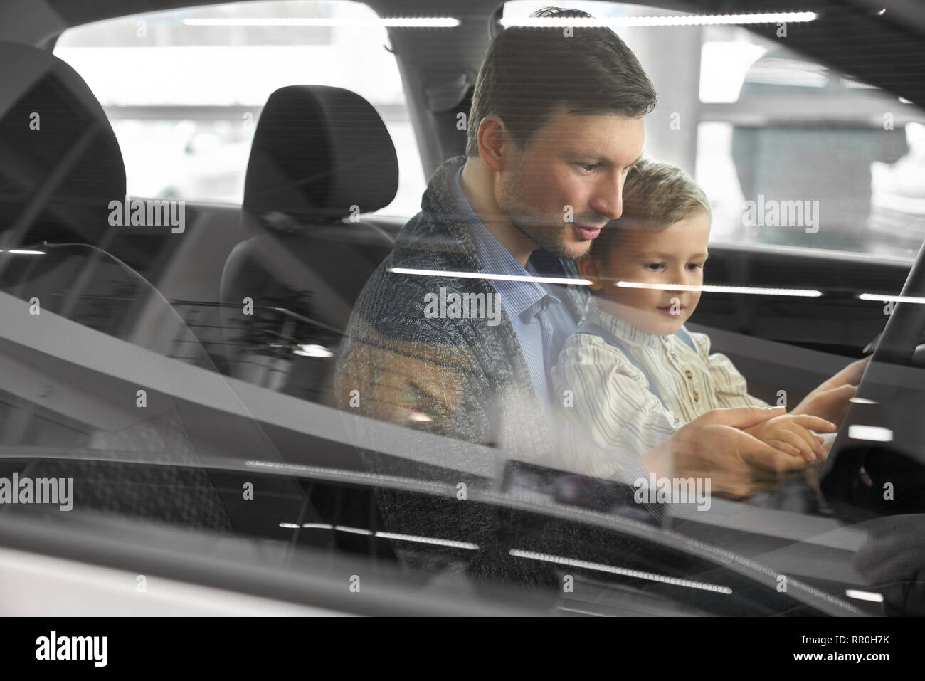 View from side window, father and son sitting inside of automobile