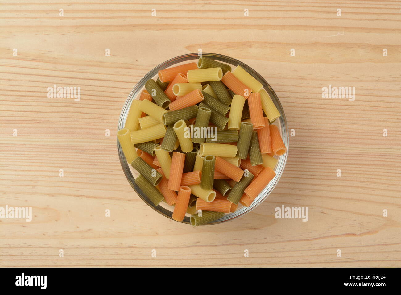Pasta tubes in a glass bowl on wooden background Stock Photo