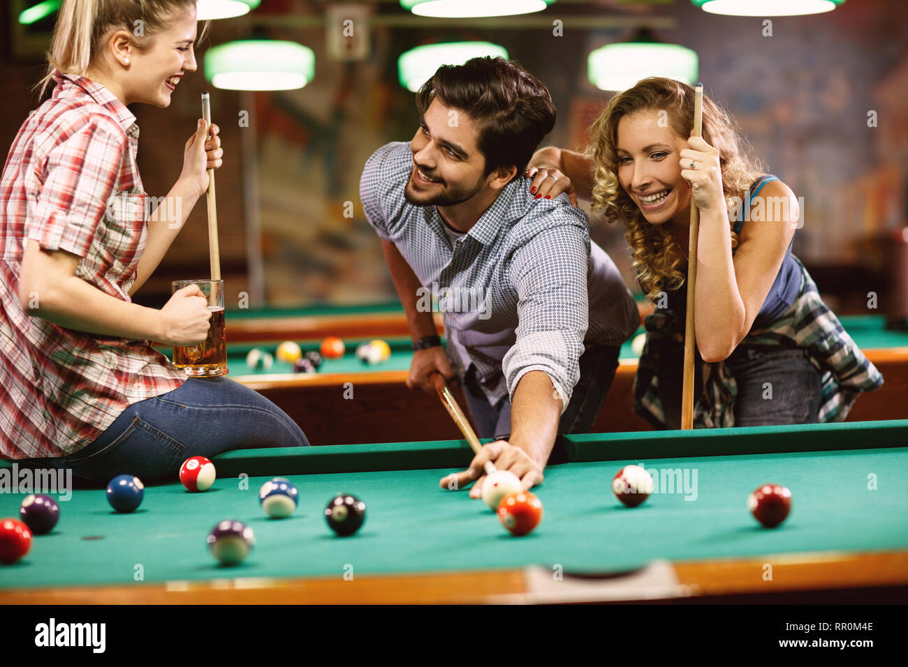 Billiards game. young friends playing pool together Stock Photo - Alamy