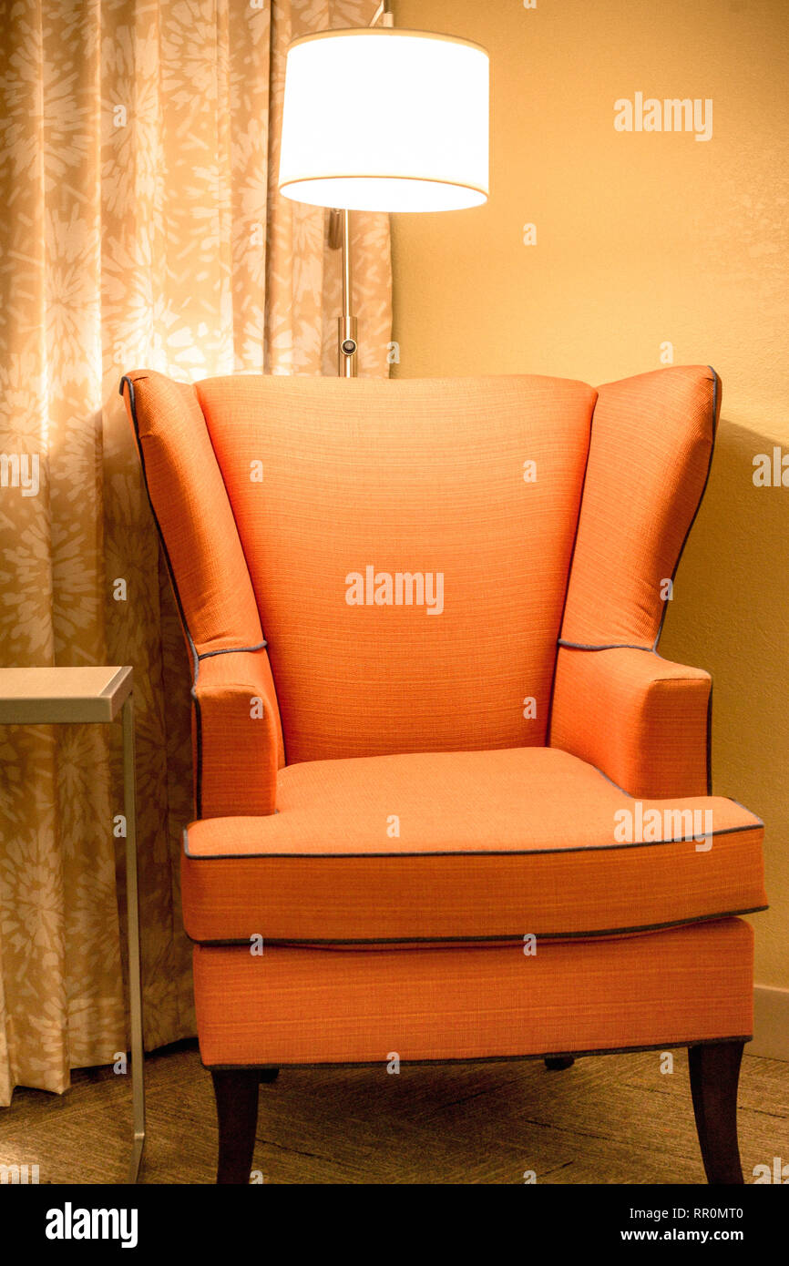 Orange upholstered armchair and light in comfortable interior setting Stock Photo