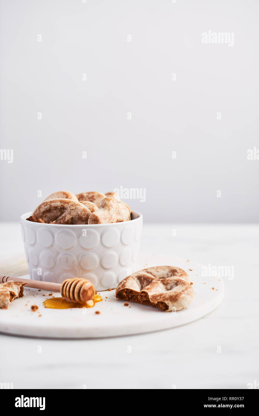 Traditional Chtristmas gingerbread cookies made of ginger, honey and cinnamon with icing in bowl on white marble table over white background. Copy spa Stock Photo