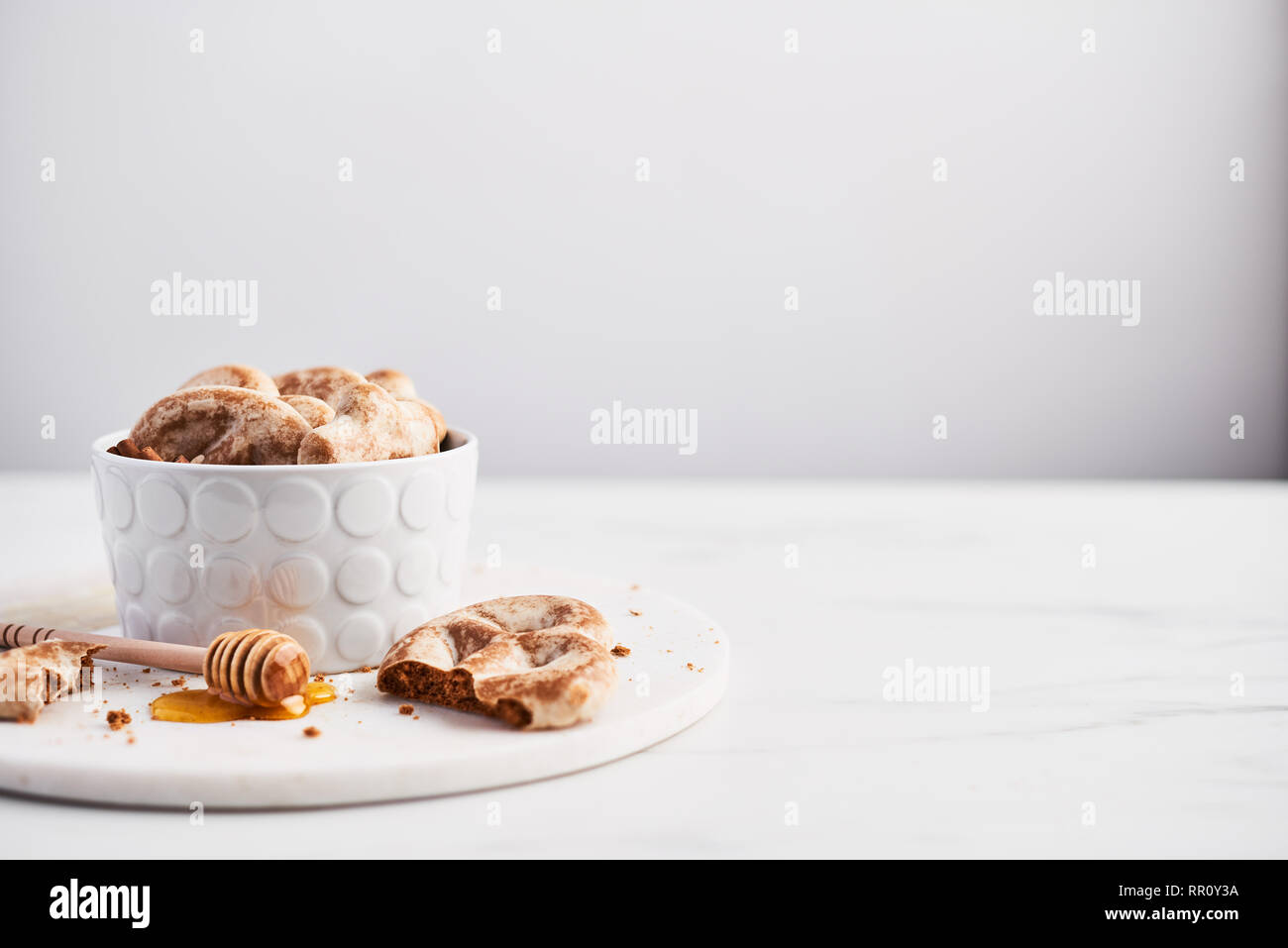 Traditional Chtristmas gingerbread cookies made of ginger, honey and cinnamon with icing in bowl on white marble table over white background. Copy spa Stock Photo