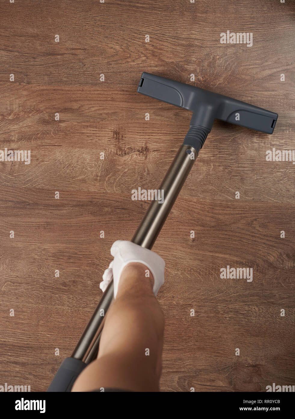 Cleaning wooden floor with vacuum cleaner. Vacuum cleaner in hand close
