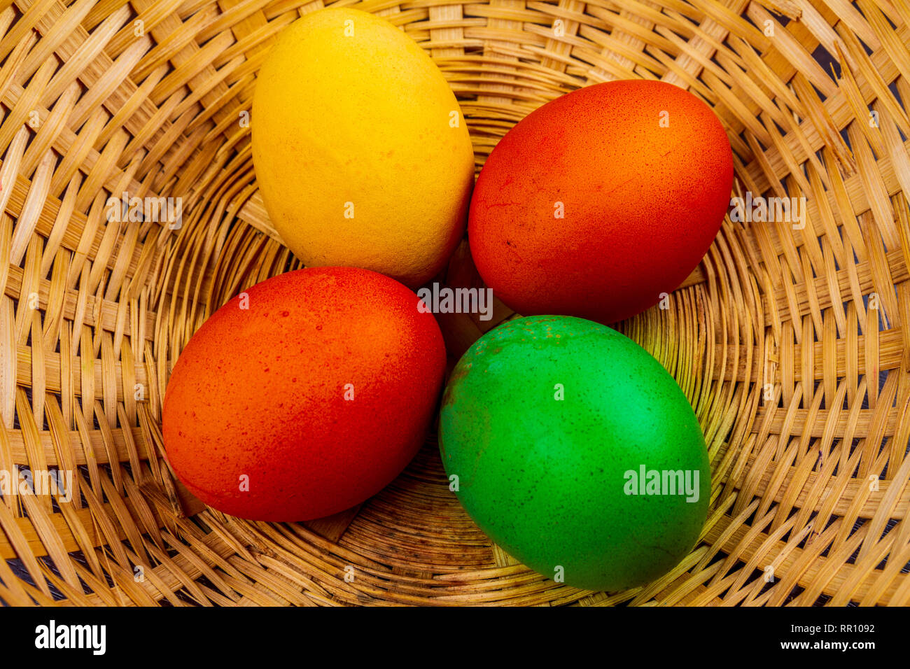 Four colorful easter eggs in basket isolated Stock Photo
