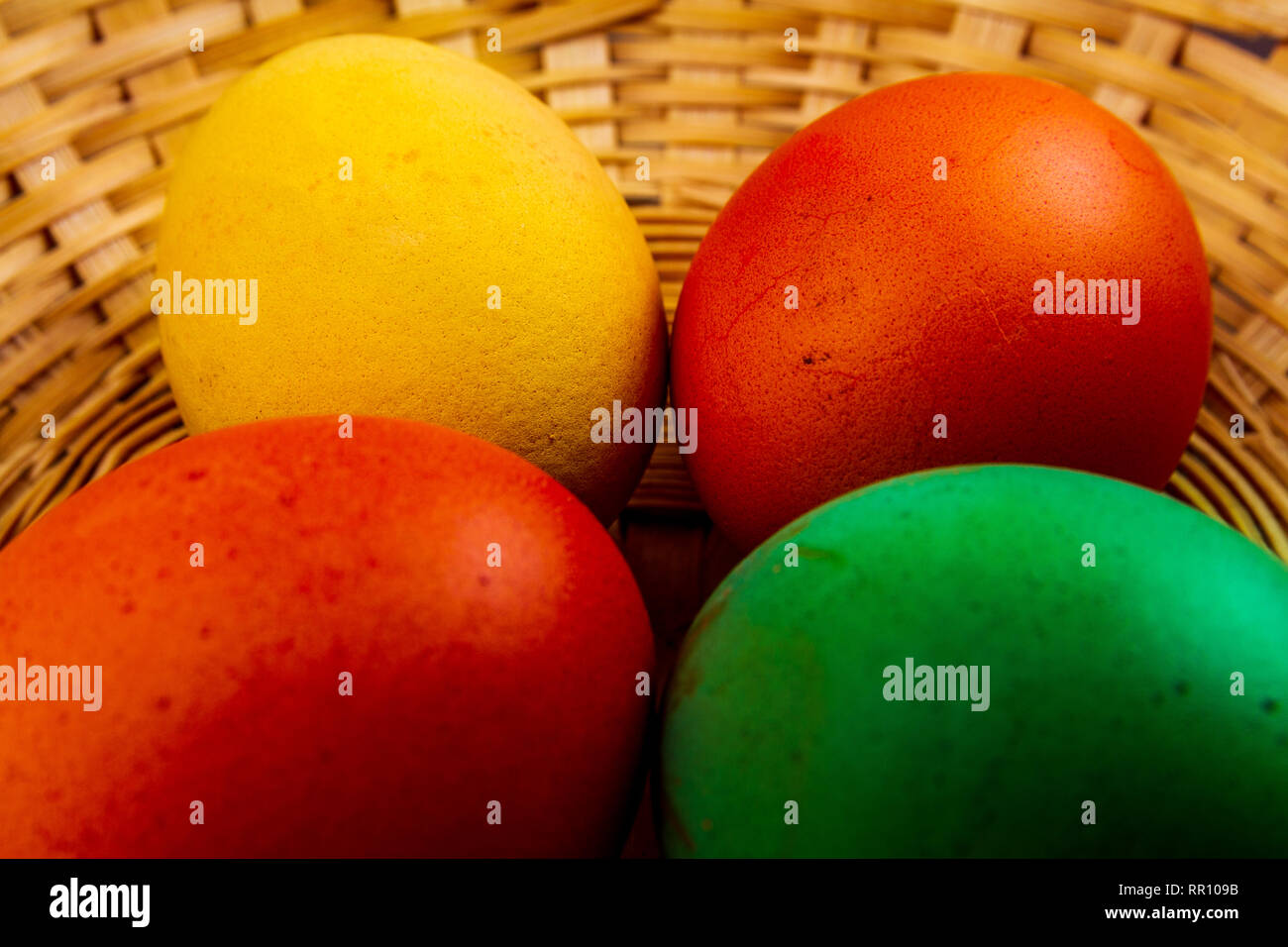 Four colorful easter eggs in basket isolated Stock Photo