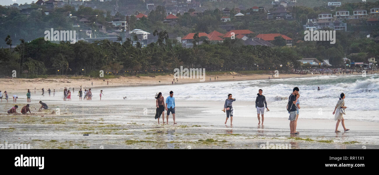 Chinese tourists on holiday vacationing at the beach at dusk in Jimbaran Bay Bali Indonesia Stock Photo