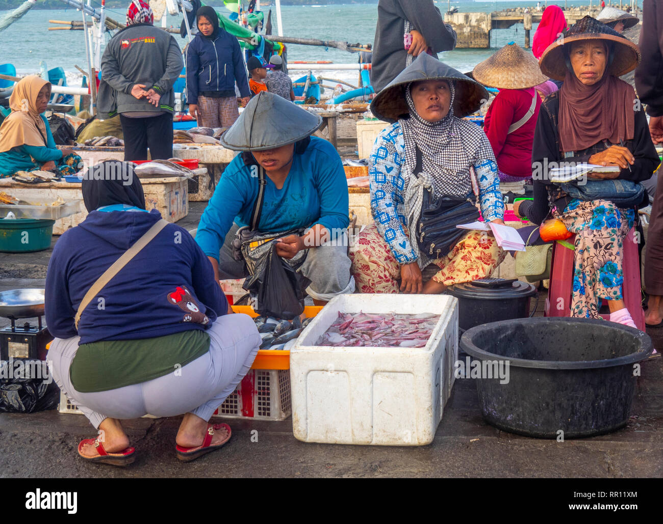 Female fishmongers wearing conical hats selling fresh fish at Kedonganan Fish Market, Jimbaran Bay Bali Indonesia. Stock Photo