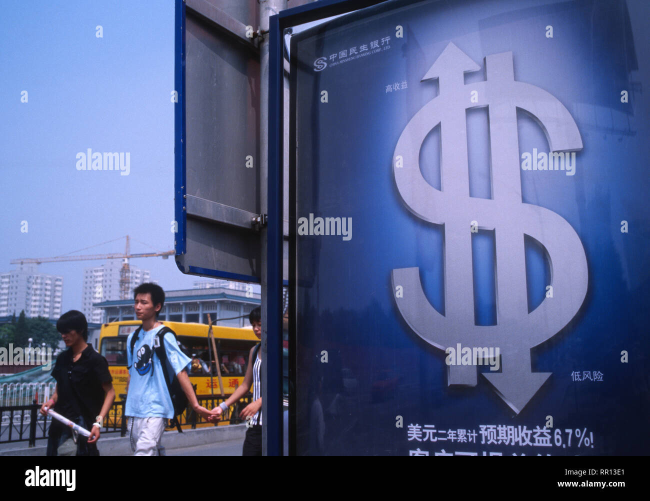 Chinese pedestrians walk past a billboard of dollar investment in Beijing, China. 2005 Stock Photo