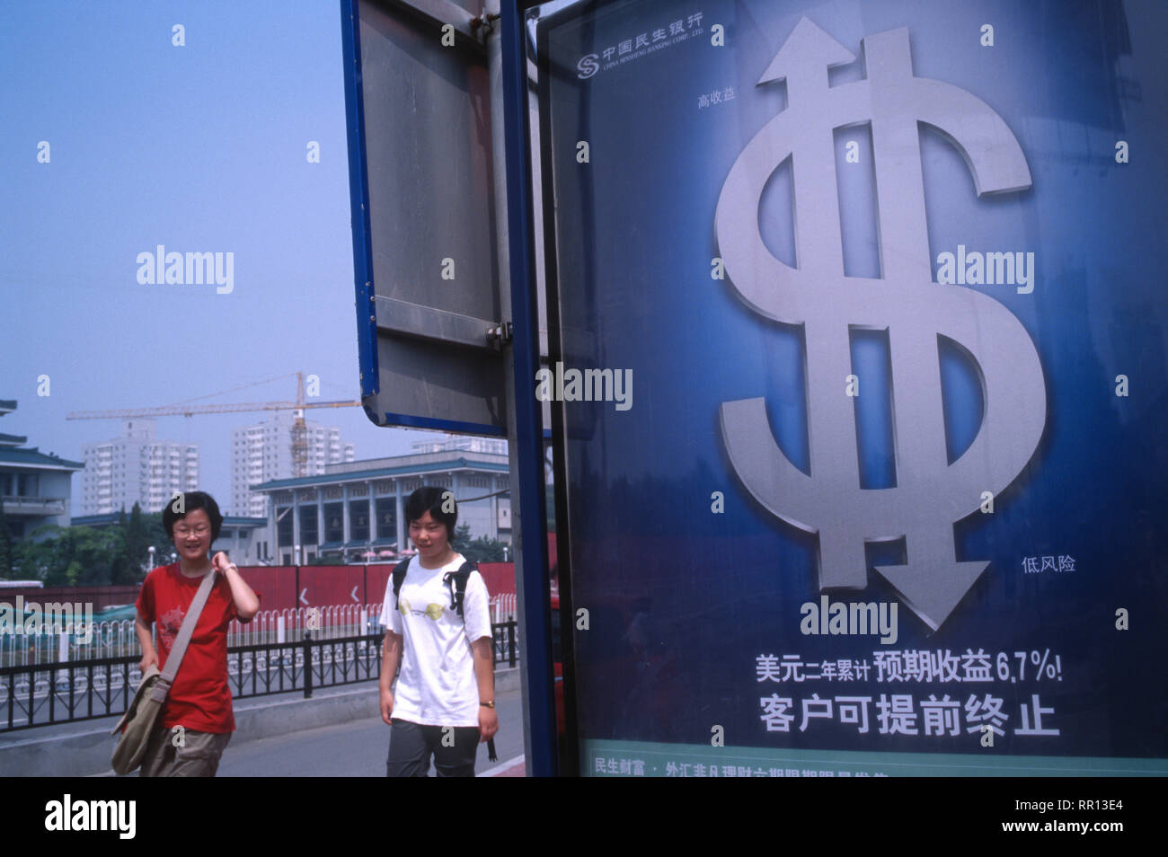 Chinese pedestrians walk past a billboard of dollar investment in Beijing, China. 2005 Stock Photo