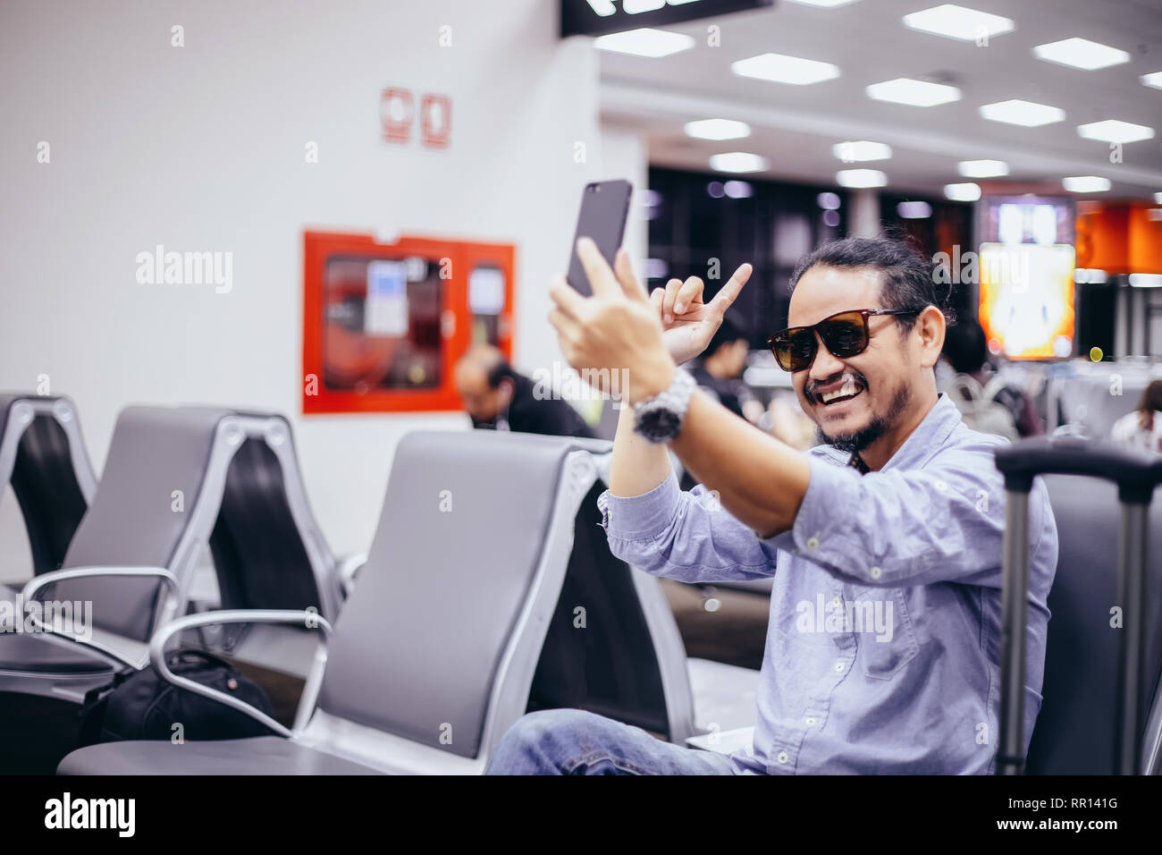 Asian man with backpack  traveler using the smart mobile phone for Video call and taking at an airport Stock Photo