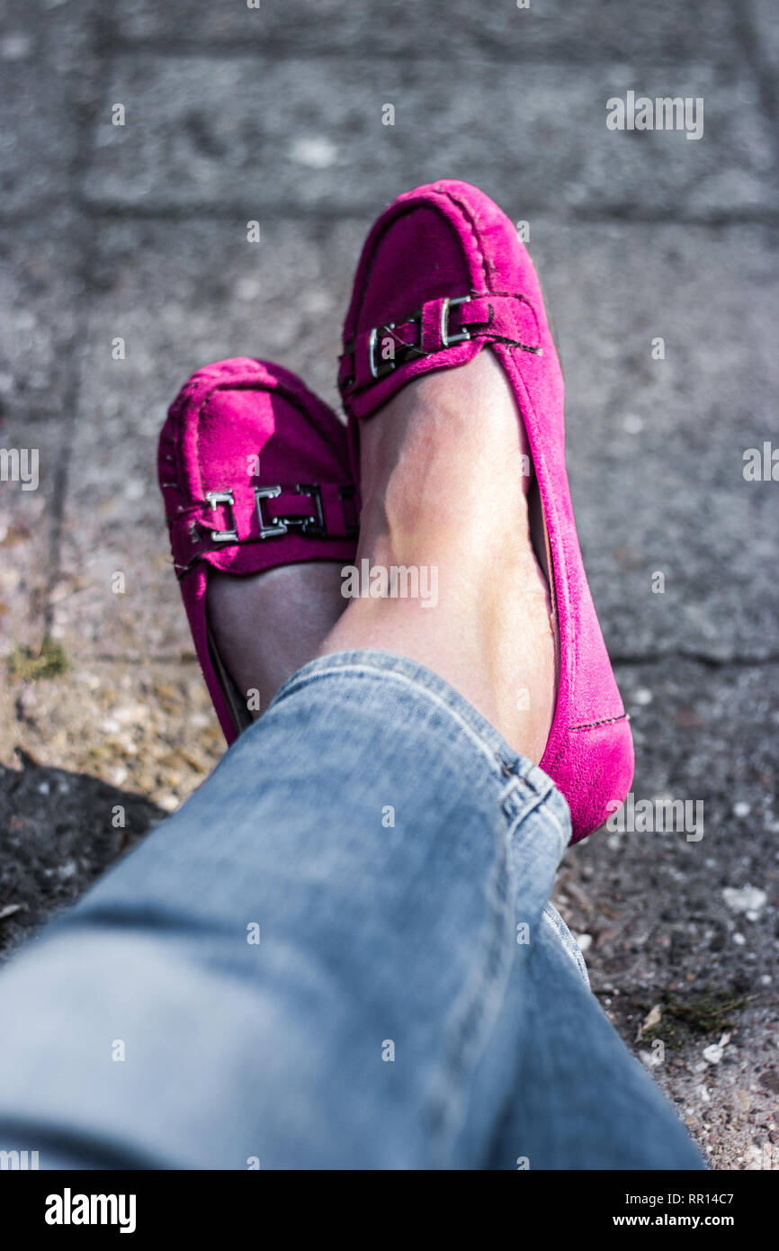 Woman's legs in Pink moccasins, sitting relaxed Stock Photo